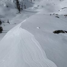 Snow eroded by the wind looks like topographic lines on a map. This area just above Heart Lake. The bowl seen here faces easterly. The ascending ridgeline to the left leads to Middle Peak.